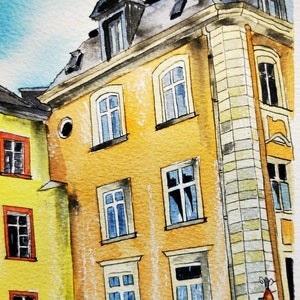 May include: Watercolor painting of European buildings with yellow and orange facades, featuring multiple windows with blue and white frames. The buildings have dark gray roofs and decorative ironwork. The sky is a light blue.