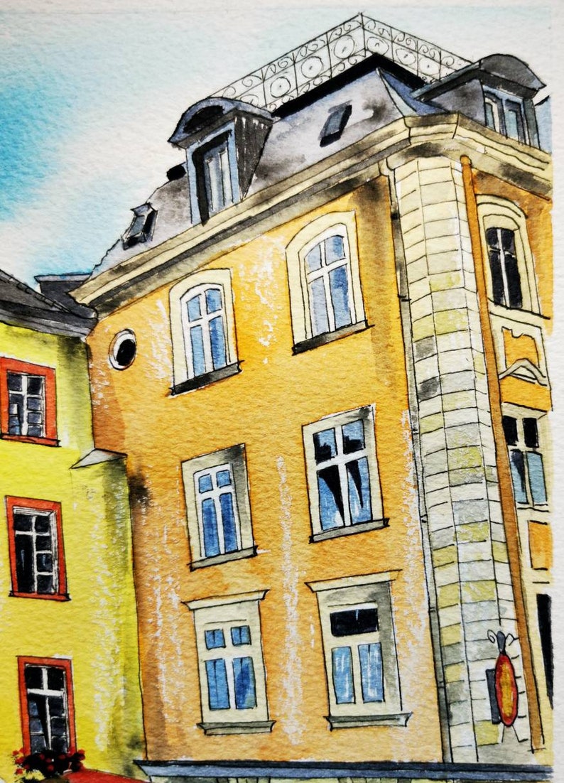May include: Watercolor painting of European buildings with yellow and orange facades, featuring multiple windows with blue and white frames. The buildings have dark gray roofs and decorative ironwork. The sky is a light blue.