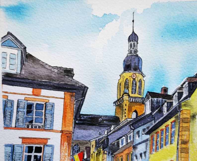 May include: Watercolor painting of a European townscape with a tall church steeple. Buildings with orange, yellow, and blue accents line the street. Blue shutters and a light blue sky complete the scene.