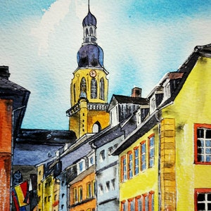 May include: Watercolor painting of a European townscape featuring a tall church steeple with a clock. Buildings in shades of yellow, orange, and blue line the street under a bright blue sky. The artwork captures the architectural details and vibrant colors.