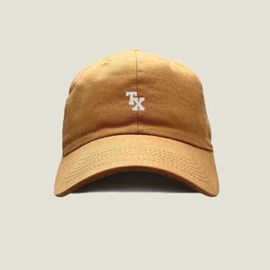 May include: A brown baseball cap with a white "TX" embroidered on the front.