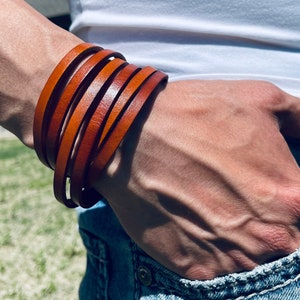May include: A brown leather bracelet with multiple strands wrapped around a wrist.