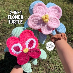 May include: Two crocheted flower turtle toys. One is pink and the other is red with white accents. Both have green leaves. The text "2-IN-1 FLOWER TURTLE" is visible in the image.  PDF PATTERN ONLY.