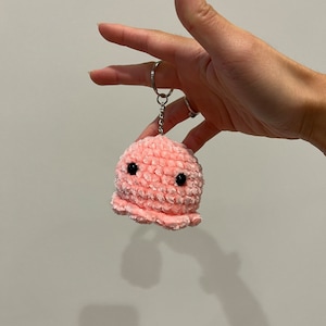 Op de afbeelding: Een roze gehaakte octopus sleutelhanger met zwarte ogen.