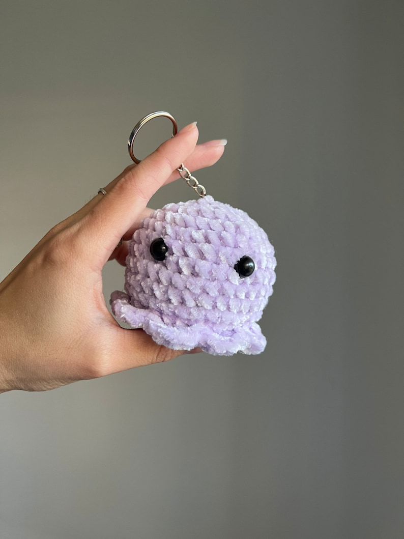 Op de afbeelding: Een paarse gehaakte octopus sleutelhanger met zwarte ogen.
