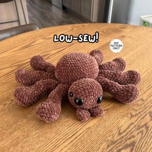 May include: A brown crocheted spider plush toy with a round body and eight legs, featuring large black plastic eyes. The text LOW-SEW! is visible above the spider, and a circular white label reads PDF PATTERN ONLY in black text.