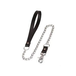 May include: A black leather strap with a silver chain and a lobster clasp. The chain is attached to the strap with a metal ring. The strap is designed to be held in the hand.