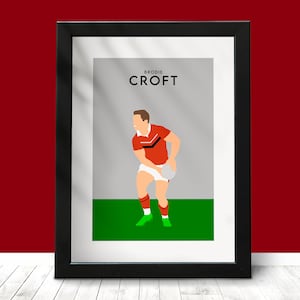 Puede incluir: Una impresión enmarcada de un jugador de fútbol gaélico con una camiseta roja y negra, sosteniendo un balón. La impresión tiene el texto "BRODIE CROFT" en la parte superior.