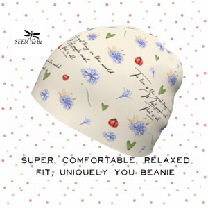May include: A beige beanie with a floral pattern and the text "The best thing in the world is that people exist. To live is the greatest thing in the world. What people are, that is all."