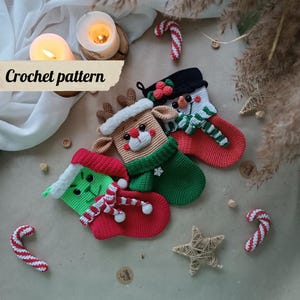 Könnte beinhalten: Häkelmuster für drei Weihnachtsstrümpfe. Die Strümpfe sind mit einem Rentier, einem Schneemann und einem grünen Monster verziert. Die Strümpfe sind rot, grün und weiß.