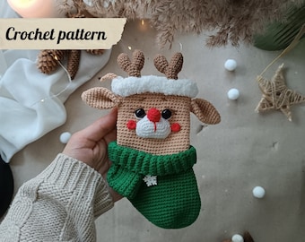 May include: A handmade crochet reindeer with a green scarf and a white fluffy trim. The reindeer has brown antlers, black eyes, and a red nose. The text "Crochet pattern" is visible in the image.