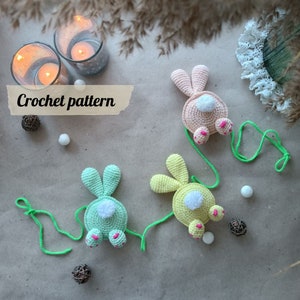 May include: Three crocheted bunny rabbit toys with colourful accents and attached strings. The bunnies are green, yellow, and pink. The text "Crochet pattern" is visible in the image.