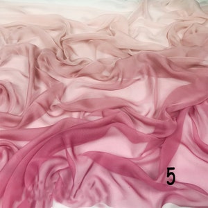 K&ouml;nnte beinhalten: Ein weicher, durchsichtiger Stoff mit einem Farbverlauf von Rosa zu Wei&szlig;. Der Stoff ist drapiert und gefaltet, was einen flie&szlig;enden und eleganten Look erzeugt.
