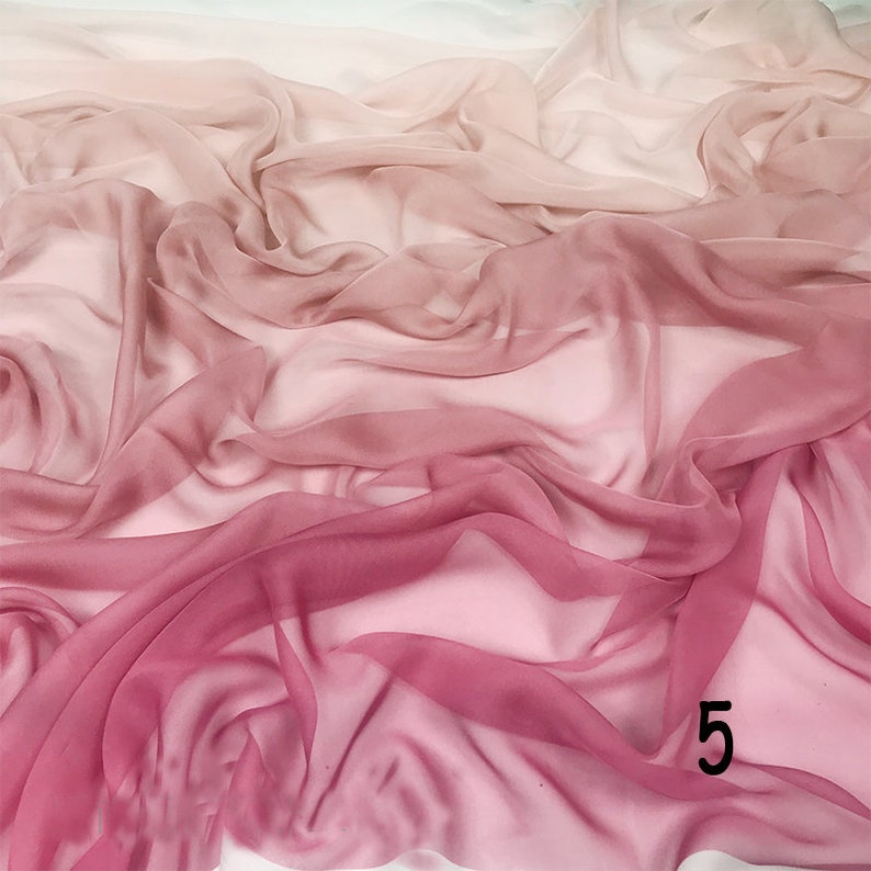 K&ouml;nnte beinhalten: Ein weicher, durchsichtiger Stoff mit einem Farbverlauf von Rosa zu Wei&szlig;. Der Stoff ist drapiert und gefaltet, was einen flie&szlig;enden und eleganten Look erzeugt.
