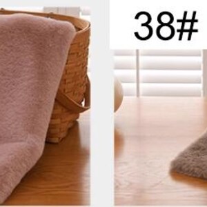 Peut inclure: Deux &eacute;charpes en fausse fourrure, l'une de couleur rose clair et l'autre de couleur marron. Les &eacute;charpes sont pli&eacute;es et plac&eacute;es sur une surface en bois.