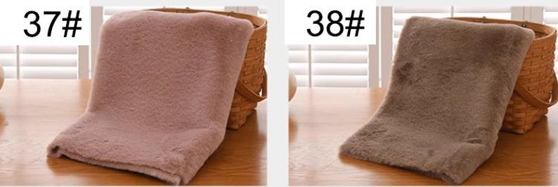 Peut inclure: Deux &eacute;charpes en fausse fourrure, l'une de couleur rose clair et l'autre de couleur marron. Les &eacute;charpes sont pli&eacute;es et plac&eacute;es sur une surface en bois.