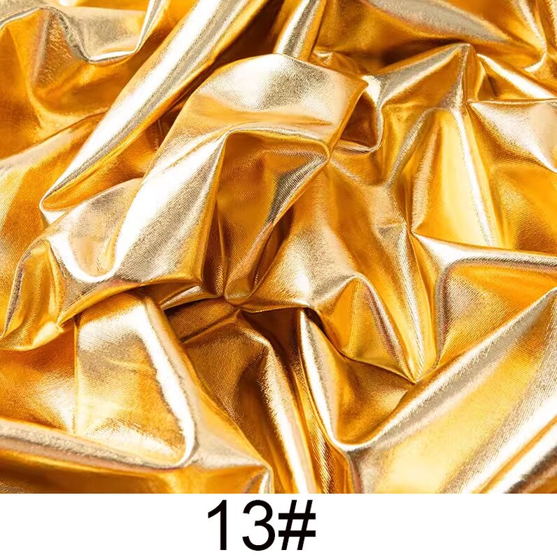 May include: Close-up of a gold metallic fabric with a wrinkled texture. The fabric is shiny and reflective. 13#