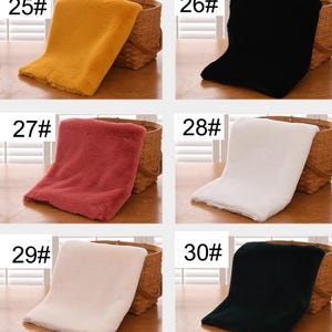 Peut inclure: Six &eacute;chantillons de tissu en fausse fourrure de diff&eacute;rentes couleurs dispos&eacute;s sur une surface en bois. Les &eacute;chantillons sont num&eacute;rot&eacute;s de 25 &agrave; 30. Les couleurs sont le jaune, le noir, le rouge, le blanc, le rose et le vert fonc&eacute;.