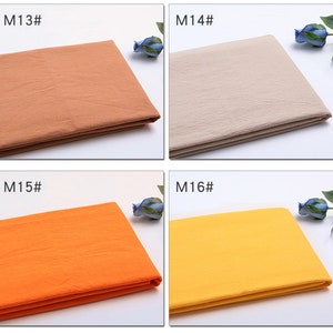 May include: Four fabric swatches in different colours: brown, beige, orange, and yellow. The swatches are folded in half and labelled with the numbers M13, M14, M15, and M16.
