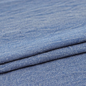 Puede incluir: Primer plano de una tela vaquera azul con una textura sutil. La tela est&aacute; doblada por la mitad, mostrando el tejido y el color azul claro.