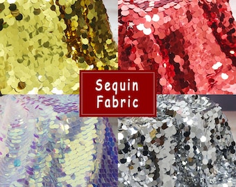 May include: Four swatches of sequin fabric in gold, red, iridescent, and silver. The fabric is made of small, round sequins.