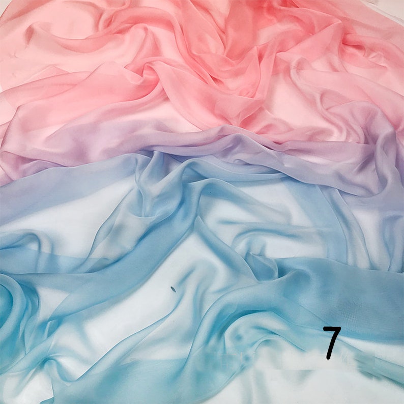 K&ouml;nnte beinhalten: Ein durchsichtiger Stoff mit einem Farbverlauf von Rosa, Lila und Blau. Der Stoff ist drapiert und gefaltet, wodurch ein weicher und flie&szlig;ender Look entsteht.