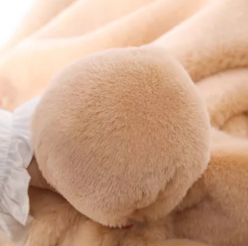 Peut inclure: Gros plan sur un tissu en fausse fourrure doux et brun clair. La fourrure est tr&egrave;s moelleuse et duveteuse, avec une texture lisse et uniforme.