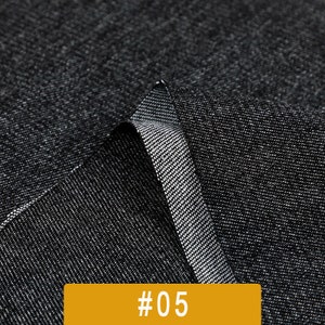 May include: Close-up of a black fabric with a textured weave. The fabric is folded over itself, showing the underside of the material. The fabric is labeled with the number #05.