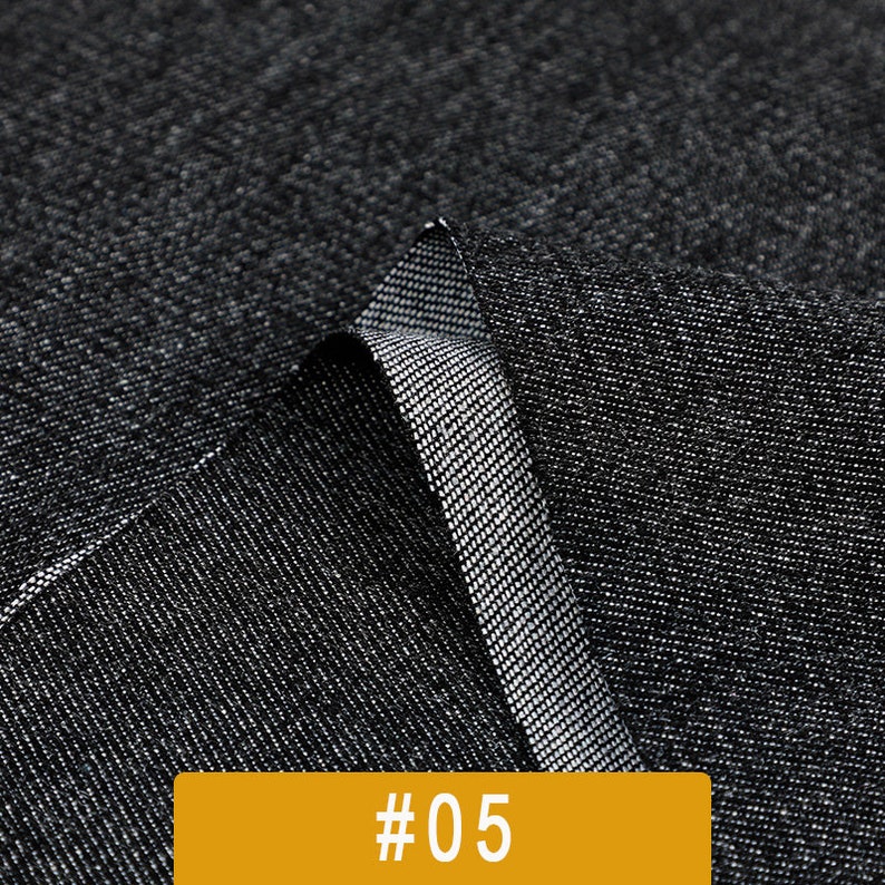 May include: Close-up of a black fabric with a textured weave. The fabric is folded over itself, showing the underside of the material. The fabric is labeled with the number #05.