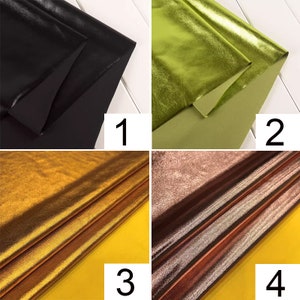 May include: Four samples of metallic fabric in different colors: black, green, gold, and brown. The fabric is folded and displayed on a white and yellow surface.