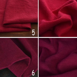 May include: Close-up of a deep red fabric with a textured weave. The fabric is folded and draped, showing the texture and colour.