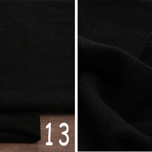 May include: Black fabric with a textured surface. The fabric is folded and the number 13 is visible in the bottom right corner.