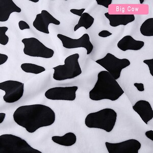 May include: White fabric with a black and white cow print pattern. The fabric is soft and plush.