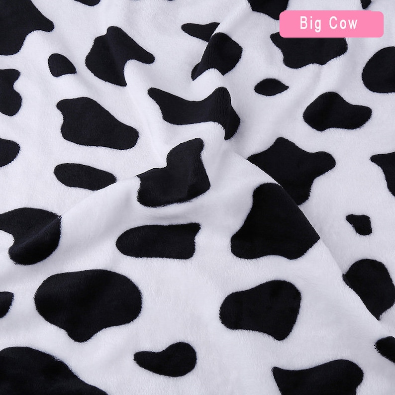 May include: White fabric with a black and white cow print pattern. The fabric is soft and plush.