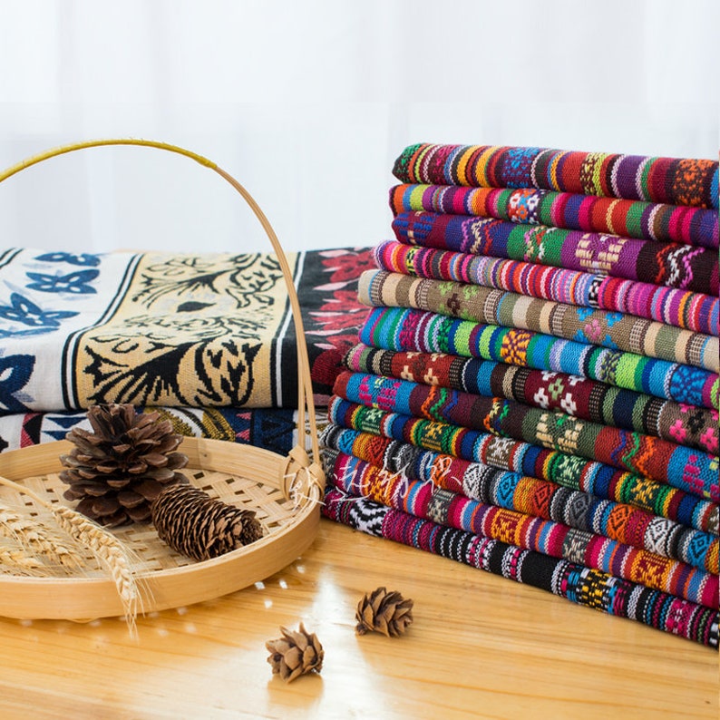 May include: A stack of colorful fabric with geometric patterns. The fabric is woven with stripes and intricate designs in shades of red, blue, green, yellow, and brown.