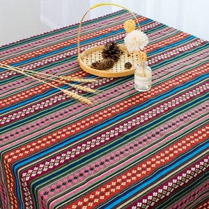 May include: A colorful striped tablecloth with a geometric pattern. The tablecloth is made of cotton and has a woven texture. It is perfect for adding a touch of bohemian style to your dining room.