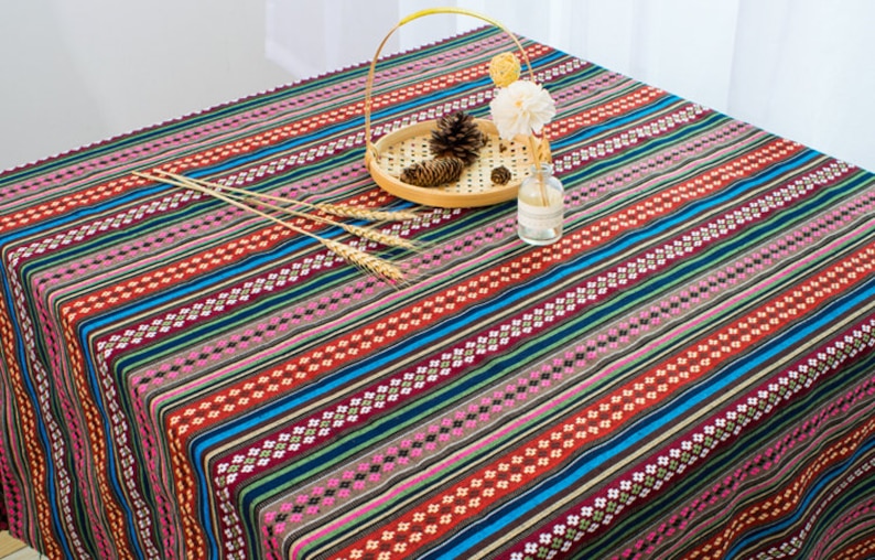 May include: A colorful striped tablecloth with a geometric pattern. The tablecloth is made of cotton and has a woven texture. It is perfect for adding a touch of bohemian style to your dining room.