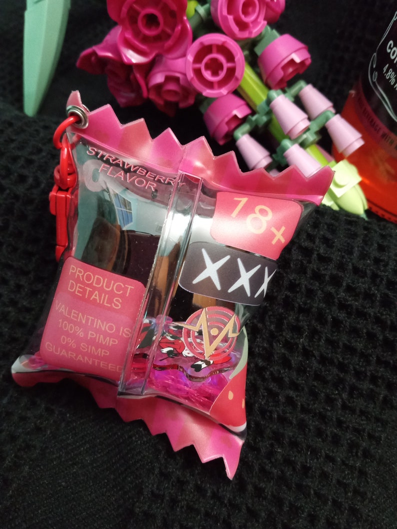 Puede incluir: Una bolsa de pl&aacute;stico rosa con cierre de cremallera y una etiqueta de sabor a fresa. La bolsa contiene un peque&ntilde;o recipiente de pl&aacute;stico transparente con un dise&ntilde;o rosa y rojo. El recipiente tiene el texto "18+ XXX" y "VALENTINO IS 100% PIMP 0% SIMP GUARANTEED" impreso en &eacute;l.