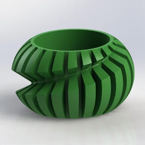 Puede incluir: Un cuenco decorativo verde y esférico con un diseño único. El cuenco presenta cortes rectangulares verticales alrededor de su circunferencia, creando una superficie texturizada. La abertura tiene un diámetro de aproximadamente 10 cm.