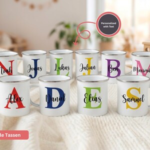May include: White enamel mugs with black lettering and colorful initial letters and names. The mugs are personalized with names like Noah, Jonas, and Alex. The text "Personalized with Text" is in a circle.