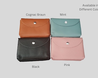 May include: Four small leather wallets in different colors: cognac brown, mint, black, and pink. Each wallet has a single snap closure.
