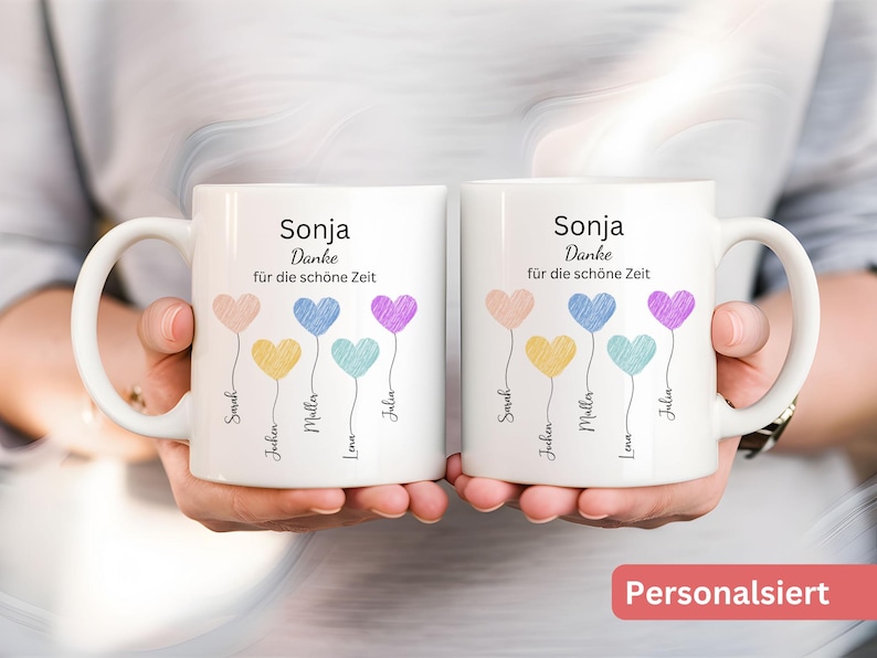 May include: Two white ceramic mugs with handles, each decorated with heart-shaped balloons in pastel shades. The mugs are printed with the name "Sonja" and the phrase "Danke f&uuml;r die sch&ouml;ne Zeit", plus names beneath the balloons.