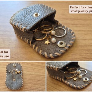 May include: A small, gray leather pouch with a snap closure, filled with rings and small jewelry. The pouch is stitched with a contrasting light-colored thread. The text "Practical for everyday use" and "Perfect for coins, rings, small jewelry, pills etc." are visible.