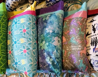 May include: A row of six colorful pillowcases with different patterns. The pillowcases are made of fabric and have a variety of designs, including flowers, unicorns, and a camouflage pattern. The pillowcases are all lined with a contrasting color of fabric.