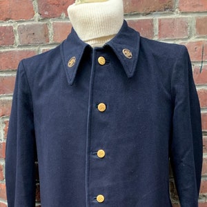 May include: A long, dark blue coat with gold buttons and embroidered details on the collar.