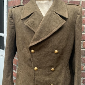 May include: A brown double-breasted wool coat with gold buttons. The coat has a high collar and a long length.