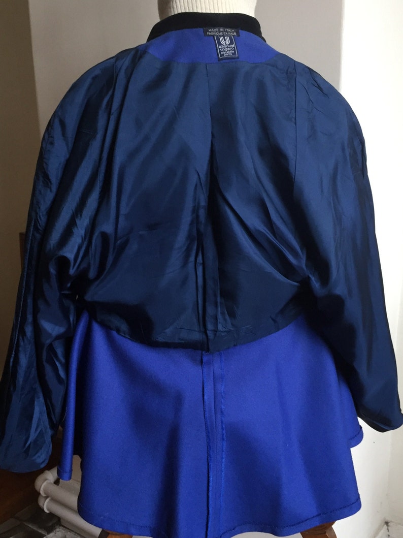 May include: A blue blazer with a black collar and a blue skirt. The blazer has a label that reads "Made in Italy" and "Wrangler Fashion Italy".