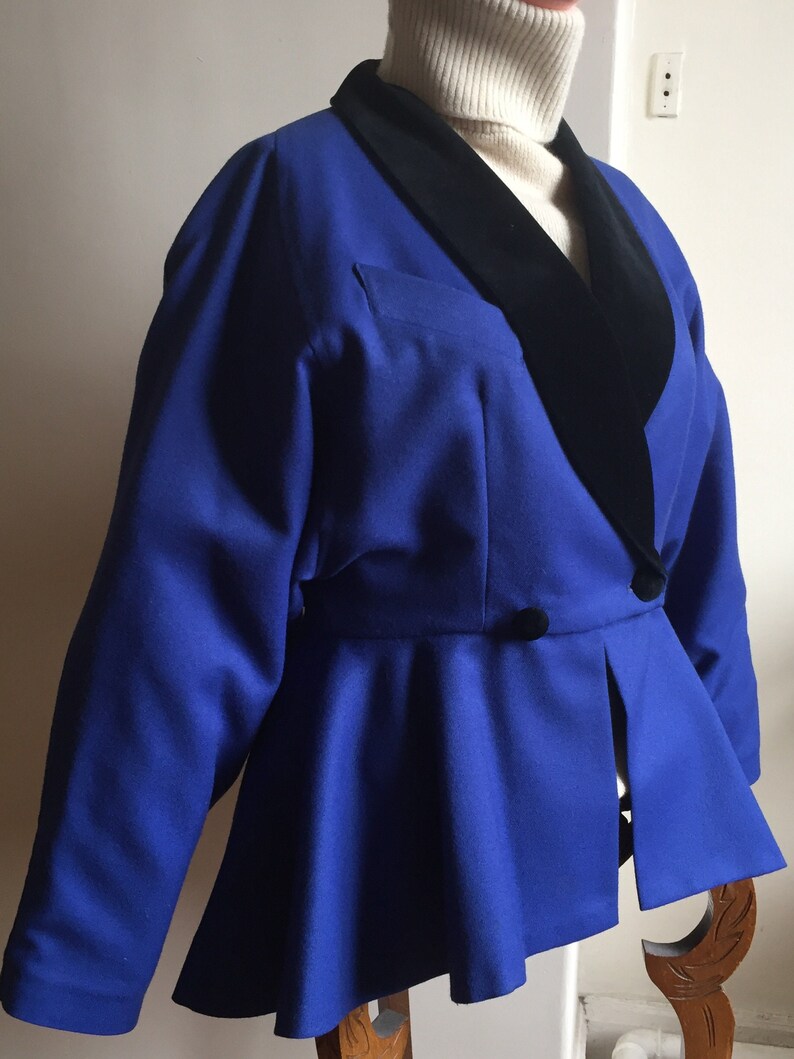 May include: A blue blazer with a black velvet collar. The blazer has a fitted bodice and a flared skirt.