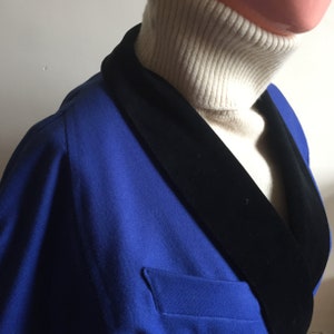 May include: A blue blazer with a black velvet collar. The blazer has a single button fastening and a pocket on the left side.