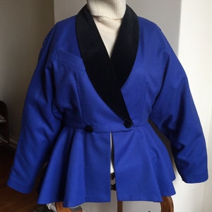 May include: A blue blazer with a black velvet collar. The blazer has a peplum hem and two buttons at the waist.